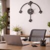 Abstract SHIU black designer clock styled on a white wall above a contemporary wooden office desk with a laptop and mesh chair.