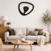 Statement SHIU asymmetrical black designer clock mounted on a white brick accent wall above a beige sofa in a contemporary living room.