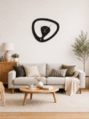 Statement SHIU asymmetrical black designer clock mounted on a white brick accent wall above a beige sofa in a contemporary living room.