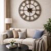 Oversized SHIU bronze Roman numeral clock serving as a statement piece over a modern beige sofa in a cozy living room.
