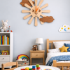 Playful SHIU wooden sun and cloud clock mounted on a light blue wall as playful decor in a brightly lit child's bedroom setup.