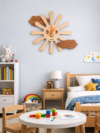Playful SHIU wooden sun and cloud clock mounted on a light blue wall as playful decor in a brightly lit child's bedroom setup.