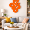 Oversized bright orange numeric collage wall clock styled as a vibrant centerpiece above a grey sofa with colorful accent pillows in a modern living room.